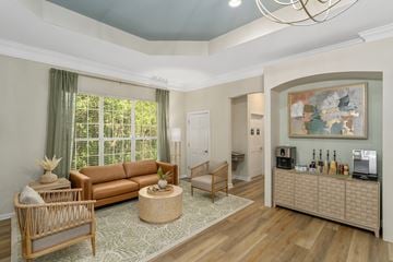 Biloxi apartment for rent - A living room with a brown sofa, a wooden chair, a wicker table, and a painting on the wall.