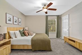 Biloxi apartment for rent - A bedroom with a bed, a ceiling fan, and a window with green curtains.