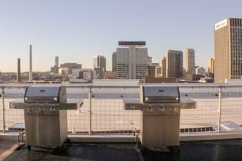 Two grills on the roof of a building with a city in the background