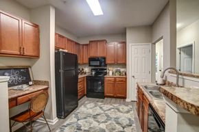 Fayetteville apartment for rent - A kitchen with brown cabinets and a black refrigerator.