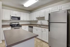 Tuscumbia apartment for rent - A kitchen with white cabinets and a stainless steel refrigerator.
