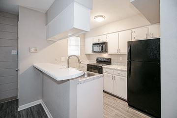 Little Rock apartment for rent - a kitchen with white cabinets and a black refrigerator
