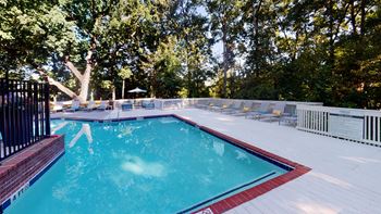 Sparkling pool with expansive sundeck and chaise lounges.