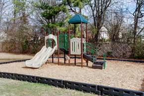 Athens townhouse for rent - A playground with a green roof, a slide, a wooden swing set, and a sandbox.