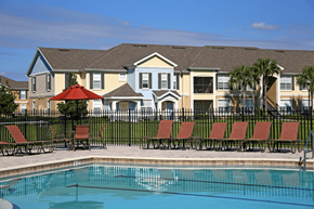 Mt. Dora apartment for rent - a swimming pool with chairs in front of an apartment building