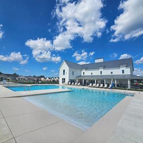 Foley apartment for rent - a large swimming pool with a white building in the background at The Cottages at Foley Farms apartments in Foley, AL