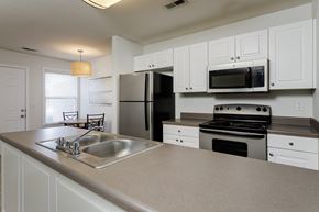 Tuscumbia apartment for rent - A kitchen with white cabinets and a black refrigerator.