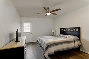 Tuscumbia apartment for rent - A bedroom with a bed, a television, and a ceiling fan.