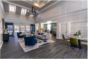 Mcdonough apartment for rent - A spacious living room with a dark blue sofa and a chandelier.