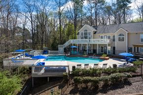 Hoover apartment for rent - Large outdoor pool surrounded by trees, lounge chairs and umbrellas with staircase access to the clubhouse at Summerchase at Riverchase in Hoover, Alabama.