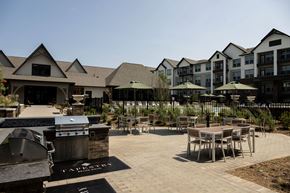 Charlotte apartment for rent - A patio with a table and chairs and umbrellas is surrounded by a fence and buildings.