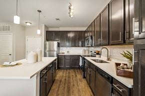 Baton Rouge apartment for rent - A modern kitchen with dark brown cabinets and stainless steel appliances.