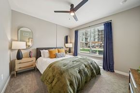 Birmingham apartment for rent - A bedroom with a bed, a ceiling fan, and a window with a view of a building outside.