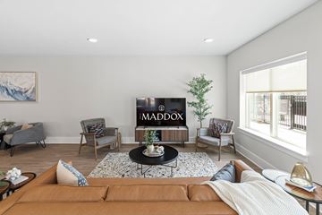 Raleigh apartment for rent - A living room with a brown sofa and a TV displaying the word "MADOX".