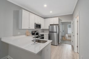 Foley apartment for rent - a kitchen with white cabinets and a stainless steel refrigerator at The Cottages at Foley Farms apartments in Foley, AL
