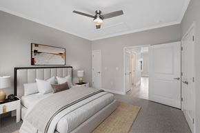 Foley apartment for rent - a bedroom with a large bed and a ceiling fan at The Cottages at Foley Farms apartments in Foley, AL