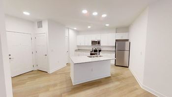 Open-concept floor plan with wood plank flooring and island kitchen.