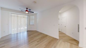 Spacious living room with ceiling fan, wood floors, and private patio access.