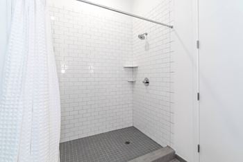 A white tiled shower in a bathroom with a shower curtain