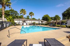 Savannah apartment for rent - A swimming pool surrounded by palm trees and a fence.
