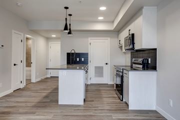 Edmonton apartment for rent - A modern kitchen with white cabinets and a wooden floor.