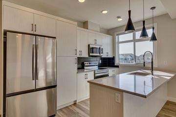 Calgary townhouse for rent - A modern kitchen with a stainless steel refrigerator and a central island.