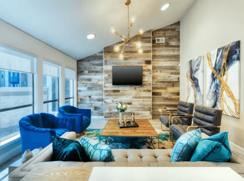 Resident clubhouse with blue cozy chairs, rock patterned wall, tv, and ample seating opportunities 