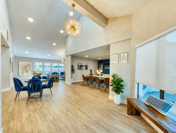 Resident clubhouse with working tables, cozy seating, and high ceilings with pendant lighting 