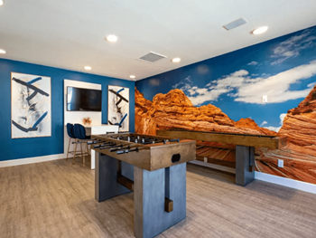 Resident game room with mountain view wall paper, foosball table, shuffleboard table,  and plank flooring 