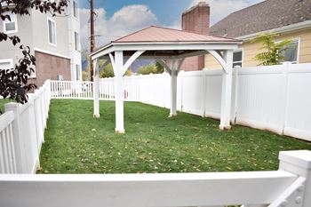 White gazebo in grassy fenced yard area
