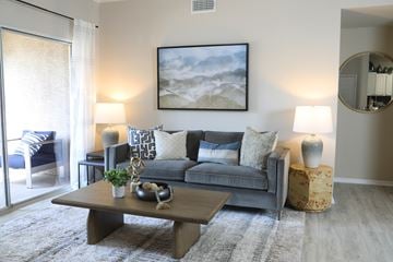 Peoria apartment for rent - A living room with a grey couch, a coffee table, and a painting on the wall.