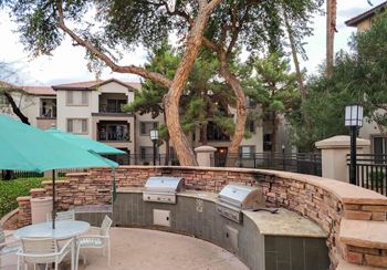 A patio with a table and chairs and a grill.