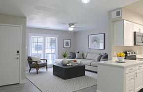 Phoenix apartment for rent - A modern living room with a grey sofa, a black coffee table, and a kitchen area with a microwave and oven.