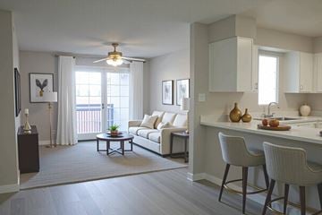 Phoenix apartment for rent - A well-lit living room with a white sofa and a dining table with chairs.