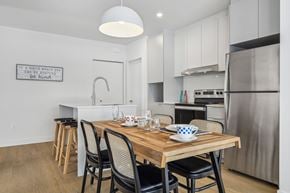 Mont-Tremblant apartment for rent - A modern kitchen with a wooden table and chairs, a stainless steel refrigerator, and a quote on the wall.