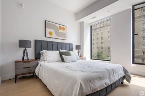 Montreal apartment for rent - A bedroom with a large bed and a city view window.