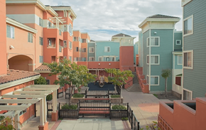 Oakland apartment for rent - A courtyard surrounded by buildings with a black fence and a tree.