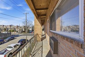 Philadelphia apartment for rent - A balcony with a brick wall and a window overlooking a street with cars and houses.