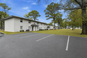Memphis apartment for rent - A parking lot in front of a white building with trees on the side.