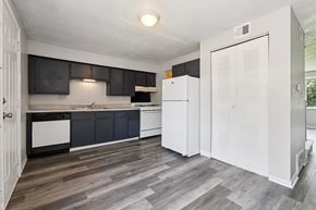 Columbus apartment for rent - A kitchen with a white fridge and black cabinets.