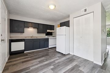 Columbus apartment for rent - A kitchen with a white fridge and black cabinets.