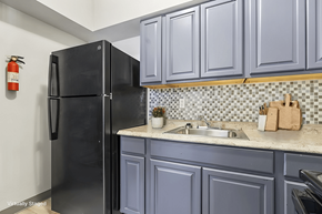 St Louis apartment for rent - A black refrigerator in a kitchen with blue cabinets.