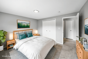 Cleveland apartment for rent - A bedroom with a large bed, a nightstand with a lamp, and a painting on the wall.