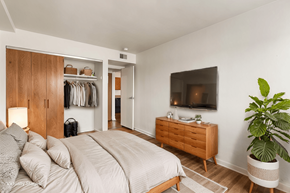 Saint Louis apartment for rent - A bedroom with a large bed, a wooden wardrobe, and a TV mounted on the wall.