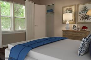 Indianapolis apartment for rent - A bed with a blue blanket is in the foreground of a room with a window and a dresser.