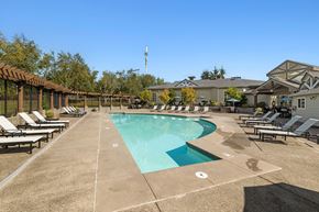 Bremerton apartment for rent - the resort style pool is surrounded by lounge chairs and umbrellas