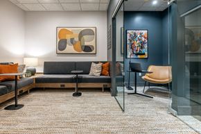 Tacoma apartment for rent - A modern office space with a grey sofa, orange pillows, and a glass wall.
