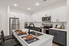 Creedmoor apartment for rent - A kitchen with a white counter top and black chairs at Enclave Creedmoor Apartments, Creedmoor