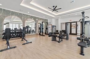 Humble apartment for rent - A spacious gym with a variety of equipment and a ceiling fan.