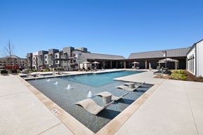 Creedmoor apartment for rent - A large swimming pool with a fountain in the middle of it at Enclave Creedmoor Apartments, Creedmoor, TX, 78610